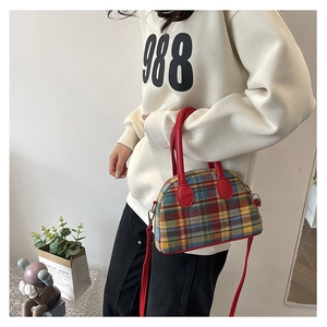 Detail of colorful plaid fabric handbag with red leather handles and metallic zipper
