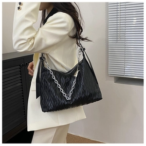 Detail view of black matelassé shoulder bag with silver chain and cute rabbit pendant