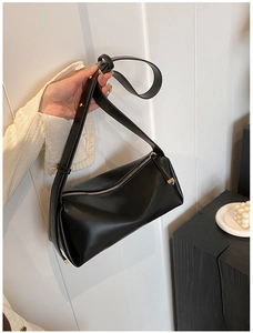 Detail view of black minimalist PU leather shoulder bag with gold metal zipper closure