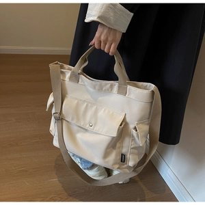 Detail of adjustable canvas shoulder strap and reinforced metal buckles on the tote bag