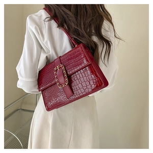 Close-up of deep red crocodile pattern leather bag with golden chain buckle detail