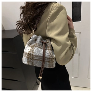 Close-up of wool plaid bucket bag featuring leather drawstring and gold metal hardware