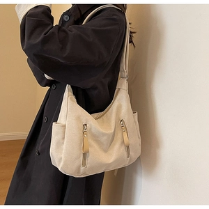 Detail of canvas crossbody bag with dual vertical zippers and long leather pullers