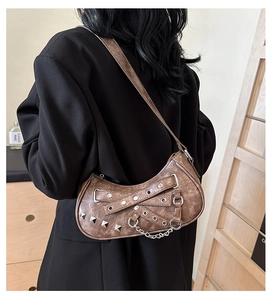 Detail of vintage brown crescent bag with punk rivets and chains worn on shoulder