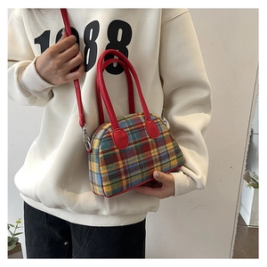 Detail of colorful plaid fabric and red leather strap on the stylish handbag