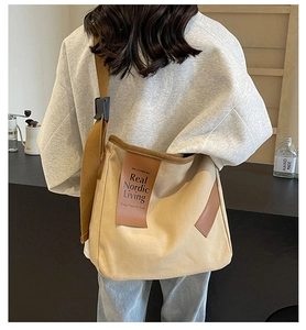 Minimalist beige canvas tote bag with brown leather accents and wide shoulder strap