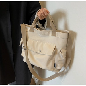 Detail of cream canvas handbag featuring dual handles and side pocket for storage