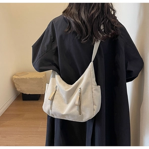 Detailed back view of a beige canvas crossbody bag showing texture and size on model