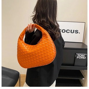 Detail of orange woven leather hobo bag with signature knot handle and Intrecciato texture