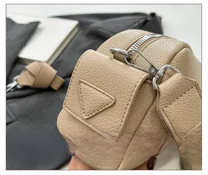 Detail showing beige litchi grain texture and silver metal hardware on a shoulder bag