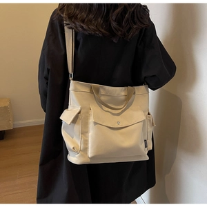 Detail of beige canvas multi-pocket crossbody bag with adjustable strap on a model