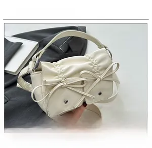 Detail view of cream PU leather handbag featuring pleated design and dual bow accents