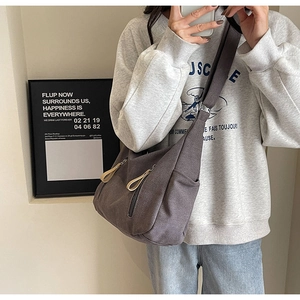 Detail view of large canvas crossbody bag featuring two vertical front zipper pockets
