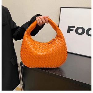 Detail of a bright orange woven hobo bag with signature intrecciato craft for fashion women