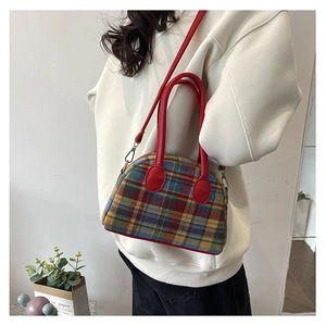 Close-up of colorful checkered fabric texture and red leather handle of the shoulder bag