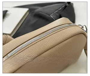 Detailed macro view of the smooth metal zipper on beige lychee pattern PU leather handbag