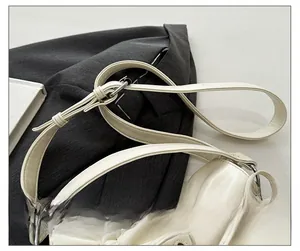 Detail of adjustable PU leather shoulder strap with silver ring buckle and side bow fold