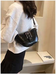 Gros plan du sac en croissant en cuir noir brillant avec boucle argentée sur un modèle