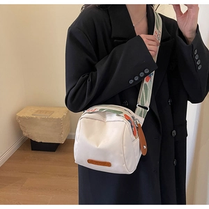 Vista dettagliata della borsa a tracolla in nylon bianco con cinturino a righe rosse
