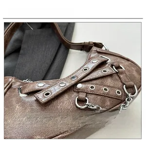 Detail of distressed brown leather with silver punk hardware and metal studs on the handbag