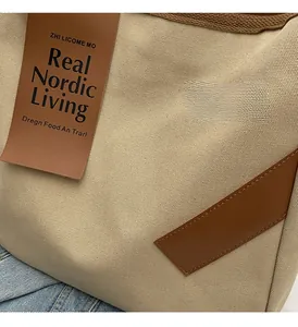 Close-up of beige canvas texture with brown faux leather brand patch and precise stitching