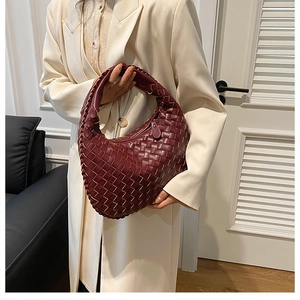 Detailed close-up of premium woven burgundy faux leather handbag with textured handle
