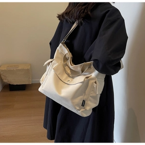 Detail view of stylish cream canvas tote bag with functional pockets and wide strap