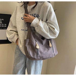 Detail view of dark grey canvas crossbody bag showing adjustable straps and front zip pockets