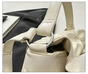 Detailed close-up of the silver metal ring connector and pleats on the beige PU handbag