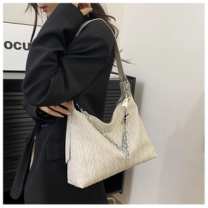 Detail of off-white quilted hobo bag with silver chain strap and rabbit charm accessory