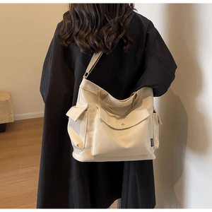 Detailed view of the multi-pocket canvas bag with side pockets and fashion brand label