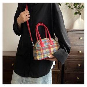 Detailed view of colorful plaid fabric and red leather trim on a dome-shaped handbag