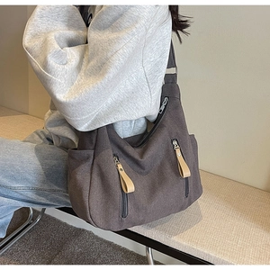 Detail of canvas crossbody bag with two front zipper pockets and leather pullers