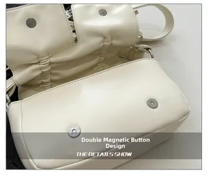 Detail showing the creamy white PU leather handbag with double magnetic buckles and folds