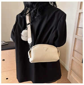 Detail view of cream white lychee leather crossbody bag with small round coin pouch on strap