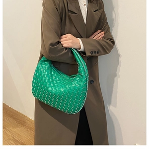 Detail of green woven hobo bag with contrast stitching on a brown blazer shoulder