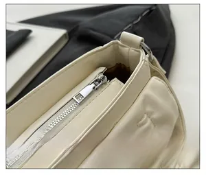 Detail of silver smooth zipper closure on off-white textured PU leather handbag