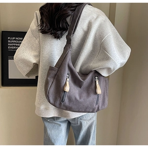 Detail of dark taupe canvas crossbody bag with twin vertical zippers and leather pulls