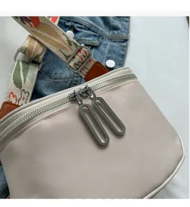Détail des fermetures éclair argentées et du tissu texturé sur le sac bandoulière crème