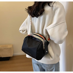 Dettaglio borsa a tracolla in nylon nero con tracolla larga a motivi colorati