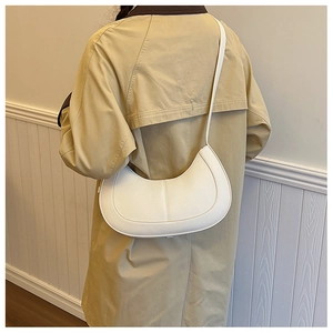 Detail of white PU leather crescent shoulder bag with lychee grain texture on a model