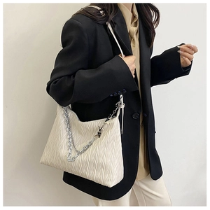 Detail view of cream pleated PU shoulder bag with bold silver metal chain on model