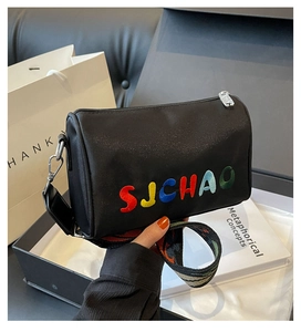 Détail du sac cylindre en nylon noir avec broderie SJCHAO colorée et large bandoulière à motifs