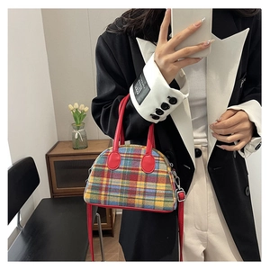 Detail of colorful plaid handbag featuring red leather trim and silver metal hardware