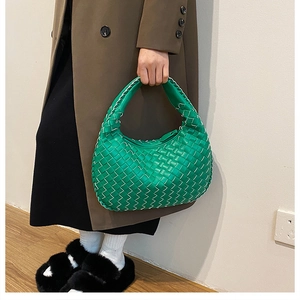 Close-up of bright green woven PU leather handbag with white stitching and hobo style