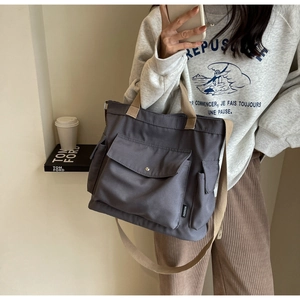 Detail of grey canvas multi-pocket tote bag with khaki straps and side storage pockets