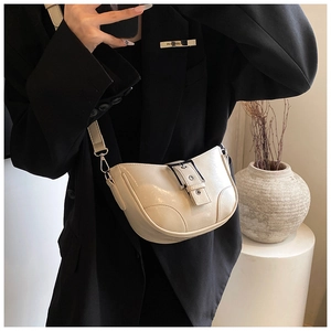 Détail du sac bandoulière beige en PU avec boucle argentée porté sur une veste de blazer noire