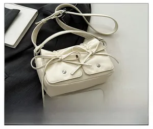 Detail showing cream PU leather handbag with dual bows and functional front flap pockets
