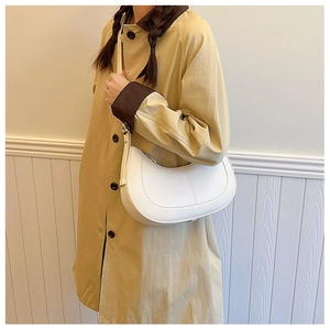 Detail of white half-moon crossbody bag showing litchi texture and shoulder strap