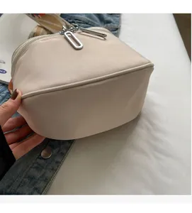 Détail du sac bandoulière en tissu crème avec doubles fermetures éclair argentées modernes